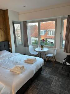 a bedroom with a bed and a table and windows at Prachtige kamer in centrum Brugge met badkamer ! in Bruges