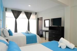 a bedroom with two beds and a flat screen tv at Hotel Tamtokow in Ciudad Valles