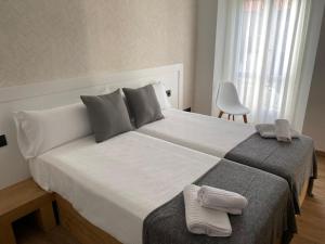 a bedroom with a large bed with two towels on it at Pensión Praza das Coles in Melide