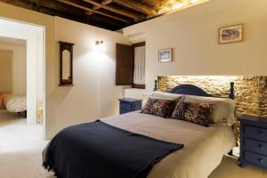 a bedroom with a bed and a stone wall at Casa Deluxe Herreros in Alcalá de Henares