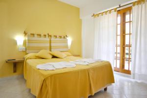 a yellow bedroom with a bed with towels on it at Apart Octogono Condominio in Villa Gesell