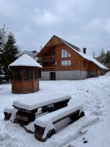 une cabane en bois avec de la neige à l'avant dans l'établissement Zrub, à Skhidnitsa