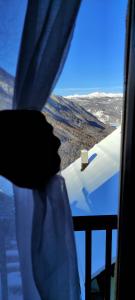 a person looking out of a window at a snow covered mountain at La Grange in Sauze di Cesana