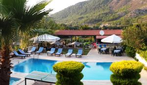 a resort with a pool and chairs and a restaurant at Erol Motel in Orhaniye