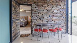 a dining room with a brick wall and a table with red chairs at Las Crucesita wine lodge in Las Compuertas