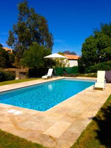 uma piscina com duas cadeiras e um guarda-sol em Villa Oliera em Saint-Florent