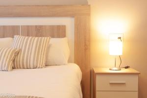 1 dormitorio con cama y mesita de noche con lámpara en AV Fernando Vela, en Oviedo