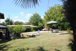 a yard with chairs and a table and an umbrella at B&B Al Castagneto in Valmontone