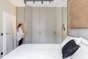 una donna in piedi in una camera con un letto di Platinum Apartment w centrum Gdyni - 5 min do plaży a Gdynia