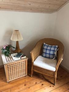 a wicker chair sitting next to a table with a lamp at Seaside Cottage Haga Park in Fröbygårda