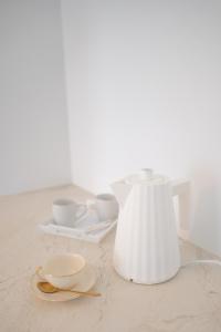 un vaso bianco seduto su un tavolo con due tazze di La Rose du Cèdre a Gray