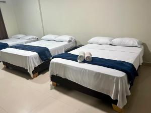 three beds with towels and slippers on them in a room at Tropical Dreams in San Andrés