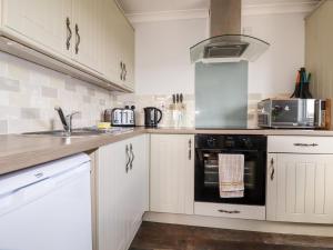 a kitchen with white cabinets and a black oven at Lowena in Saint Day