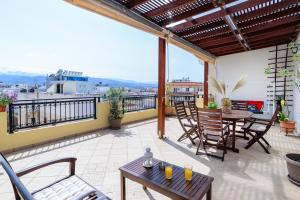 een patio met tafels en stoelen op een balkon bij Central penthouse in quiet neighborhood near sandy beach in Chania