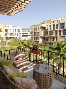 a balcony with wicker chairs and tables and a building at Sodic Westown Residence 2 in 6th Of October
