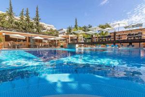 ein großer blauer Pool mit Tischen und Sonnenschirmen in der Unterkunft Balaia Beach T2 com piscina in Albufeira