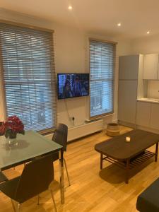 a living room with a table and a tv on the wall at Beautiful one bedroom flat in the heart of Notting Hill Gate in London