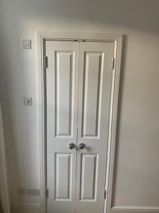 a white closet with two doors in a room at Beautiful one bedroom flat in the heart of Notting Hill Gate in London