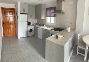 a kitchen with a white refrigerator and a dishwasher at Apartamento con terraza en primera línea de playa in Conil de la Frontera