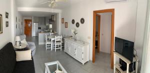 een woonkamer en een keuken met een bank en een televisie bij Apartamento con terraza en primera línea de playa in Conil de la Frontera