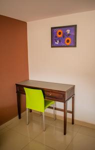 a desk with a green chair and a painting on the wall at Hotel Granda Inn in Tuxtla Gutiérrez