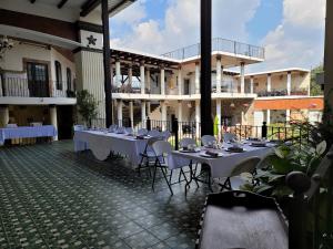a restaurant with white tables and chairs in front of a building at La Capitanía de San Pedro in Antigua Guatemala