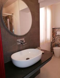 ein Badezimmer mit einem großen weißen Waschbecken und einem Spiegel in der Unterkunft CASA VERDINA, nel cuore di Alghero in Alghero