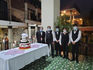 a group of people wearing face masks standing next to a table with a cake at La Capitanía de San Pedro in Antigua Guatemala +247 photos