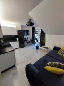 a living room with a blue couch and a kitchen at Apartament Kruklanki in Kruklanki