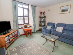 a living room with a blue couch and a tv at Watershed Cottage in Settle