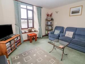 un soggiorno con un divano blu e una TV di Watershed Cottage a Settle