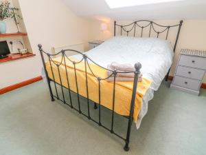 una camera da letto con un letto nero e una coperta gialla di Watershed Cottage a Settle