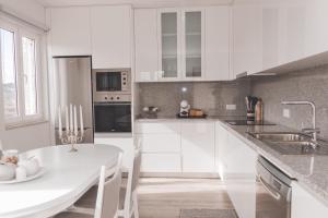 a kitchen with white cabinets and a white table at Casa do Cruzeiro Quinta do Couto in Armamar