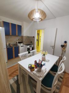 einen weißen Esstisch mit Stühlen und eine Küche in der Unterkunft Apartman Caroline in Čačak