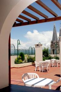 un patio con sillas y mesas blancas y una iglesia. en Provincial Plaza Hotel en Salta