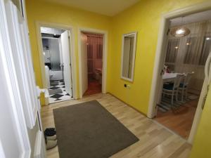 Cette chambre est dotée de murs jaunes et d'un couloir avec un tapis. dans l'établissement Apartman Caroline, à Čačak