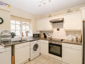 a kitchen with white cabinets and a washer and dryer at 5 Wye Rapid Cottages in Ross on Wye