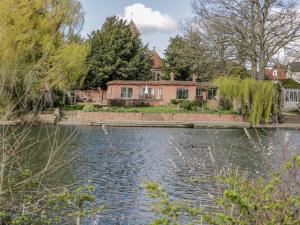 a house next to a river with a bridge at Ninea in Wallingford