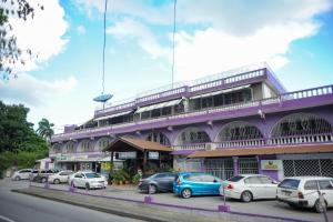 un edificio púrpura con coches aparcados delante de él en Glorianna Hotel, en Montego Bay