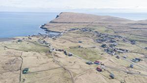 SkálavíkにあるThe Real Faroese Experienceの山の横の村の空中風景