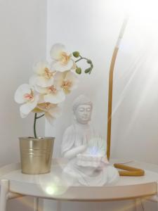 uma estátua branca sentada numa prateleira ao lado de uma flor em OmniaX Apartment em Faro
