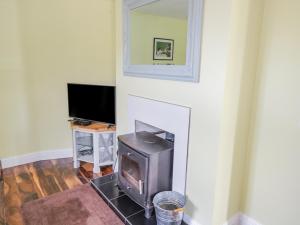 a living room with a fireplace and a television at Hannon's Country Farmhouse in Ballymote