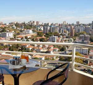 balkon ze stołem i krzesłami oraz miasto w obiekcie Hotel Mont Blanc w mieście Bento Gonçalves