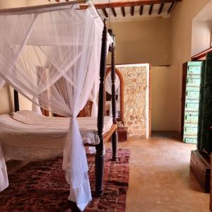 um quarto com uma cama de dossel e redes mosquiteiras em Terraço das Quitandas Design Accommodation-AL em Ilha de Moçambique