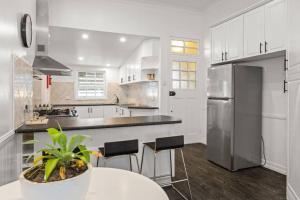 a white kitchen with a table and a refrigerator at Urban Getaway Top Floor 4BR 4BA, AC, Sauna, Ipswich in Ipswich