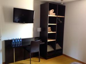 a room with a desk and a tv and a closet at Hôtel La Gibecière in Lohéac