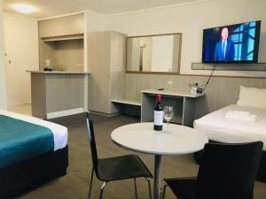 a hotel room with a table and a television at Comfort Inn Glenelg in Adelaide