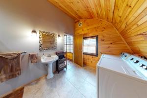 a bathroom with a white sink and a wooden ceiling at Seneca Lake Getaway in Burdett