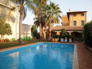 una piscina di fronte a una casa con palme di Belvilla by OYO Gabriella Catania a Floridia