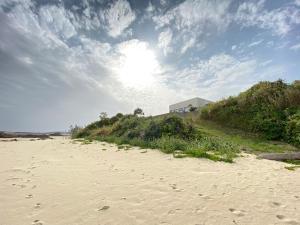 a sandy beach with the sun in the sky at ゴールデンマイルヴィラ in Amami